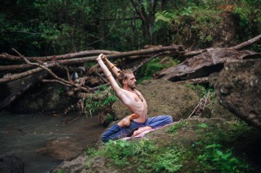 Yoga uygulaması ve doğada meditasyon. Nehir yakınlarında pratik yapan adam