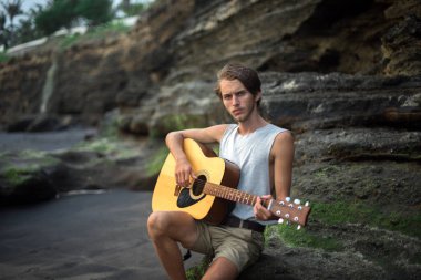 Sahilde gitar çalan romantik bir genç adam.