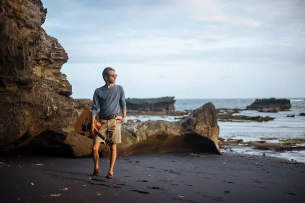 Romantische jongeman met een gitaar op het strand — Stockfoto