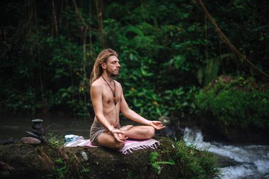 Yoga uygulaması ve doğada meditasyon. Nehir yakınlarında pratik yapan adam