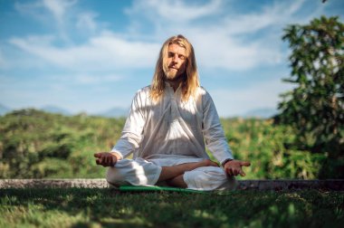Erkek, dışarıda yoga ve meditasyon pratiği yapıyor.