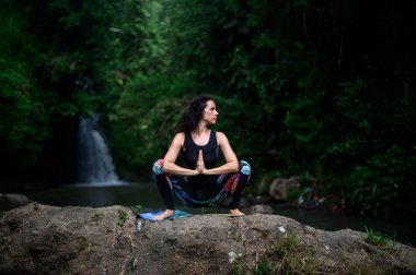Yoga ve meditasyon doğada var. Nehir kenarında pratik yapan kadın
