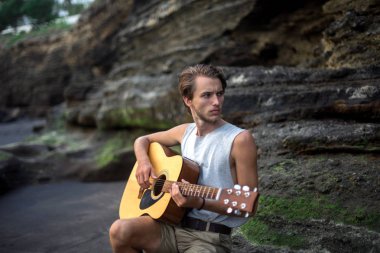 Sahilde gitar çalan romantik bir genç adam.