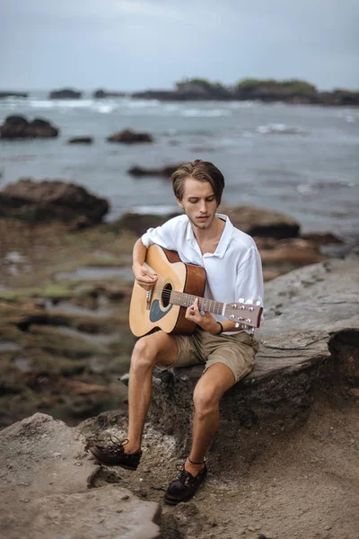 Romantische jongeman met een gitaar op het strand — Stockfoto