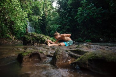Yoga uygulaması ve doğada meditasyon. Nehir yakınlarında pratik yapan adam