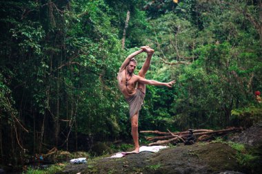 Yoga uygulaması ve doğada meditasyon. Nehir yakınlarında pratik yapan adam
