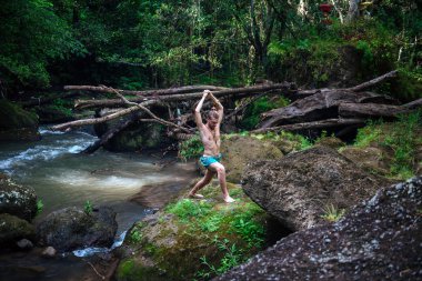 Yoga uygulaması ve doğada meditasyon. Nehir yakınlarında pratik yapan adam