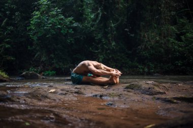 Yoga uygulaması ve doğada meditasyon. Nehir yakınlarında pratik yapan adam