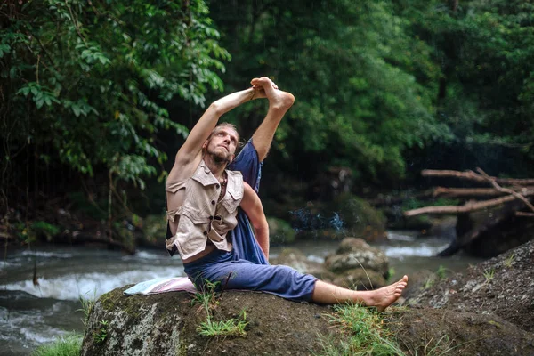 Yoga practice and meditation in nature. Man practicing near river