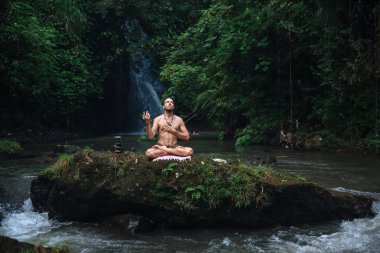 Yoga uygulaması ve doğada meditasyon. Nehir yakınlarında pratik yapan adam