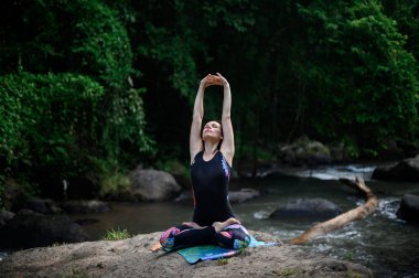 Yoga ve meditasyon doğada var. Nehir kenarında pratik yapan kadın