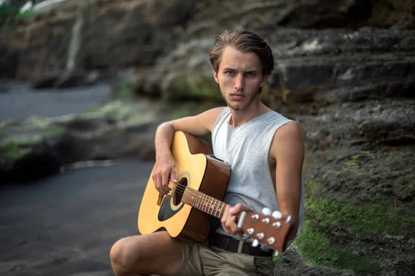 Romantische jongeman met een gitaar op het strand — Stockfoto