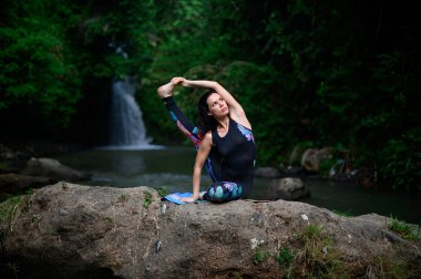Yoga ve meditasyon doğada var. Nehir kenarında pratik yapan kadın