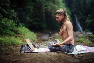 Yoga uygulaması ve doğada meditasyon. Nehir yakınlarında pratik yapan adam