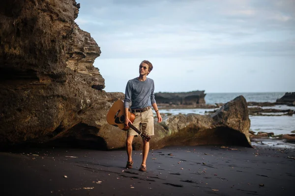 Romantische jongeman met een gitaar op het strand — Stockfoto