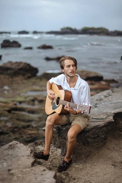 Romantic young man with a guitar on the beach — Stock Photo, Image