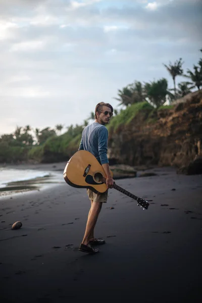 Romantische jongeman met een gitaar op het strand — Stockfoto