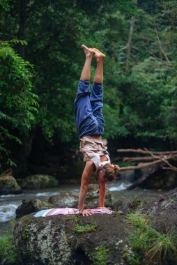 Yoga uygulaması ve doğada meditasyon. Nehir yakınlarında pratik yapan adam