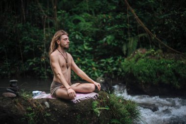 Yoga uygulaması ve doğada meditasyon. Nehir yakınlarında pratik yapan adam