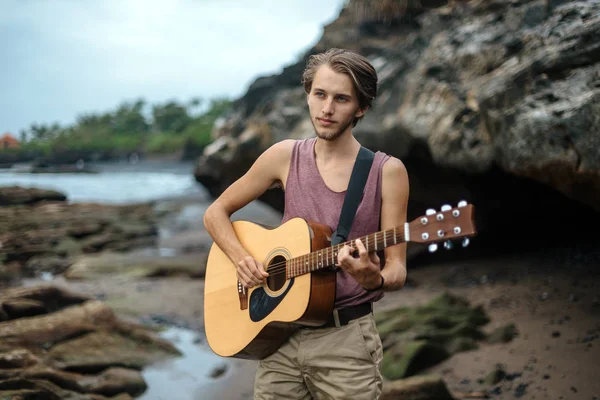 Romantische jongeman met een gitaar op het strand — Stockfoto