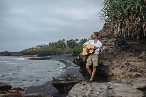 Romantische jongeman met een gitaar op het strand — Stockfoto