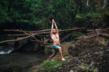 Yoga uygulaması ve doğada meditasyon. Nehir yakınlarında pratik yapan adam