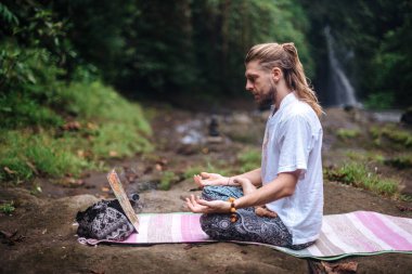 Yoga uygulaması ve doğada meditasyon. Nehir yakınlarında pratik yapan adam