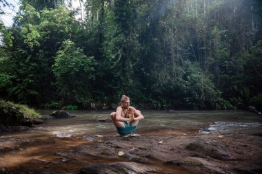 Yoga uygulaması ve doğada meditasyon. Nehir yakınlarında pratik yapan adam