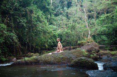 Yoga uygulaması ve doğada meditasyon. Nehir yakınlarında pratik yapan adam