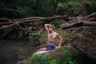 Yoga uygulaması ve doğada meditasyon. Nehir yakınlarında pratik yapan adam