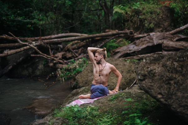 Yoga uygulaması ve doğada meditasyon. Nehir yakınlarında pratik yapan adam
