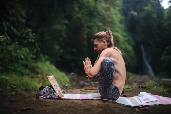 Yoga uygulaması ve doğada meditasyon. Nehir yakınlarında pratik yapan adam