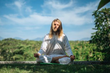 Erkek, dışarıda yoga ve meditasyon pratiği yapıyor.