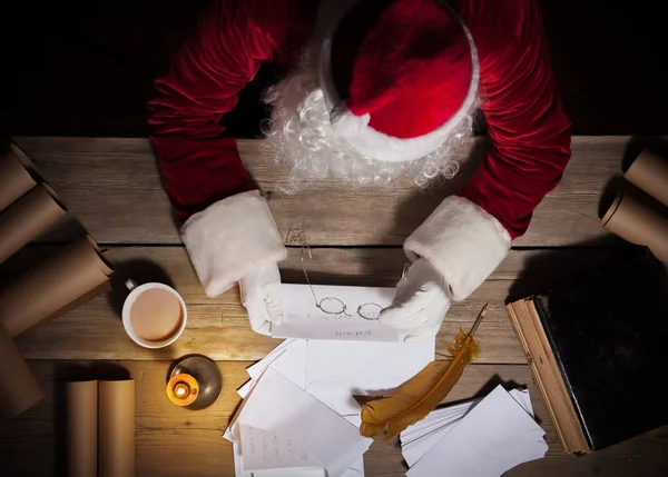 Weihnachtsmann sitzt am Tisch in seinem Zimmer und liest Weihnachtsbrief vom Kind — Stockfoto