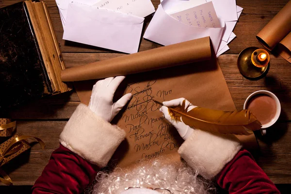 Weihnachtsmann sitzt am Tisch in seinem Zimmer und schreibt Weihnachtsbriefe oder Wunschzettel — Stockfoto