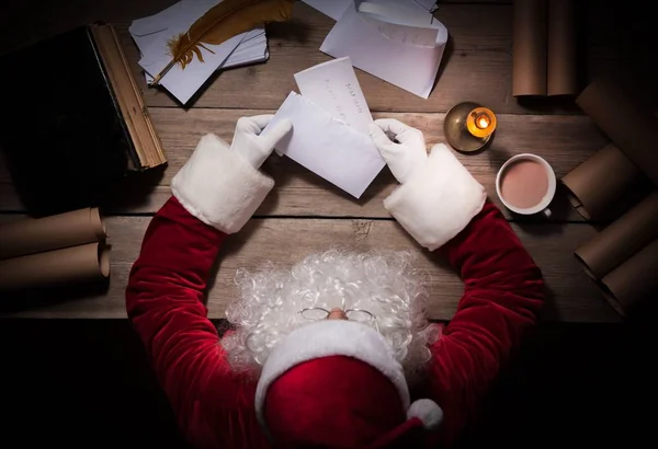 Weihnachtsmann sitzt am Tisch in seinem Zimmer und öffnet Weihnachtsbrief vom Kind — Stockfoto