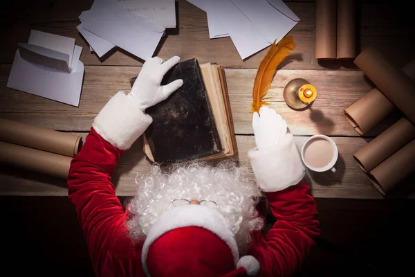 Weihnachtsmann sitzt am Tisch in seinem Zimmer und arbeitet — Stockfoto