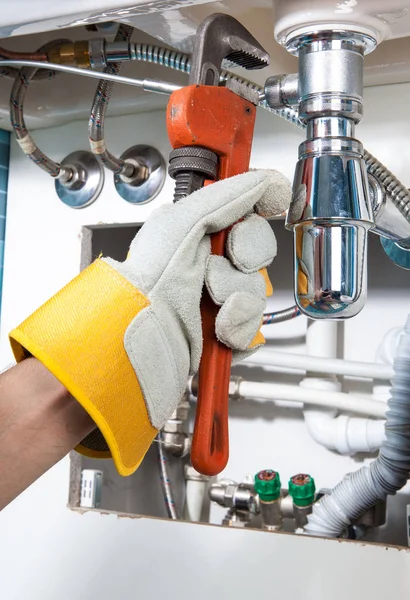 Lavabonun altında bir boru onarılıyor. Tesisatçı