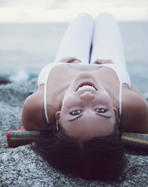 Fille en blanc est couché sur la plage et souriant, coucher de soleil — Photo