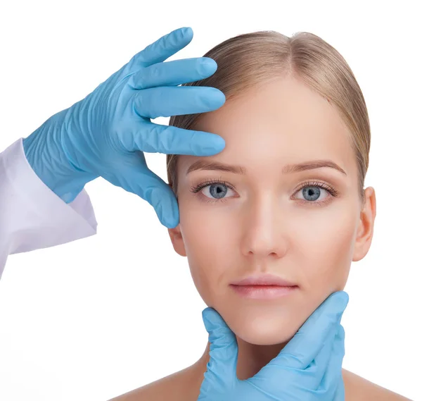 Handen van een chirurg aan het gezicht te raken mooie vrouw, close-up — Stockfoto