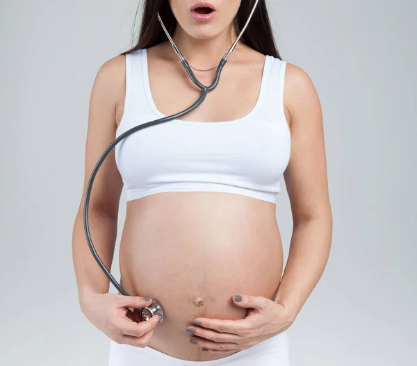 Mulher grávida ouvir barriga por estetoscópio — Fotografia de Stock