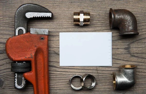 Комплект сантехнических инструментов и визитная карточка на деревянном фоне — стоковое фото