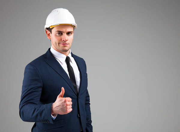 Портрет бизнесмена в белом шлеме на сером фоне

