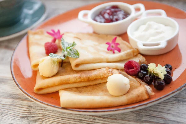 Panqueques con crema y mermelada y bayas frescas en un plato —  Fotos de Stock