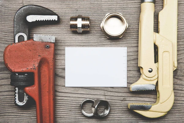 Conjunto de accesorios de tuberías de plomería y tarjeta de visita en el fondo de madera — Foto de Stock