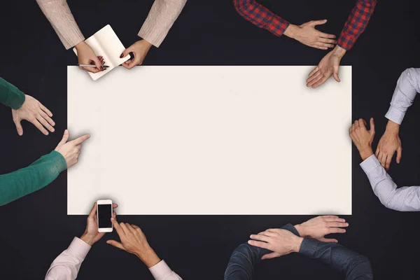 Conceito de trabalho em equipe e cooperação - visão superior de seis pessoas desenhando ou escrevendo em uma grande folha branca em branco no quadro negro . — Fotografia de Stock