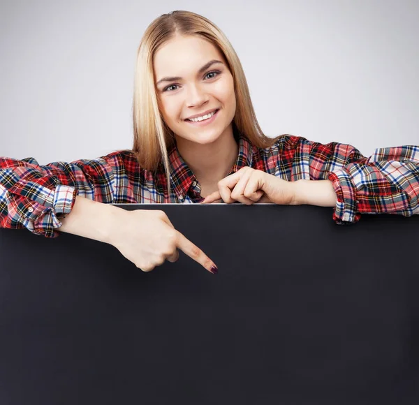 Uśmiechnięty młody nastolatek blond dziewczyna przytrzymaj czarny czysty papier i pokazuje na niej. — Zdjęcie stockowe