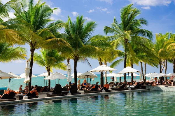 Chaises longues avec parasols près de la piscine contre l'océan — Photo
