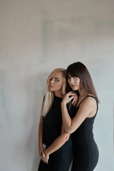Zwei hübsche Frauen in einem schwarzen Kleid drinnen — Stockfoto