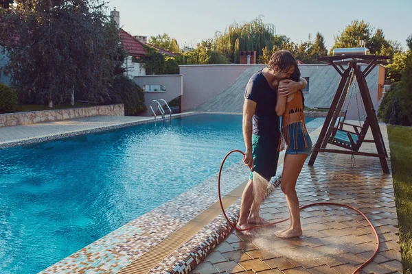 Paar hat Spaß dabei, sich mit Gartenschlauch zu übergießen — Stockfoto